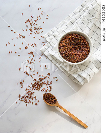 Brown rice in a white bowl and in a wooden spoon Brown rice in a white bowl and in a wooden spoon 44153008