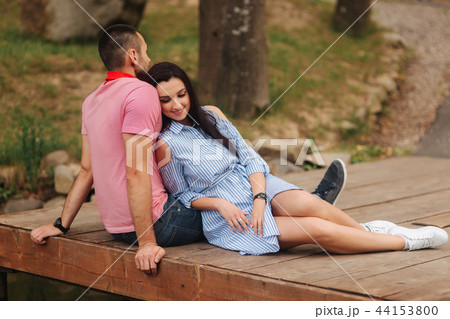A guy and a girl enjoy each other in a romantic atmosphere, sits on the pier 44153800