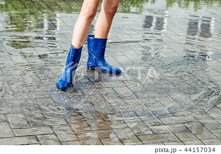 girl in rubber boots standing in a puddle after a rain 44157034