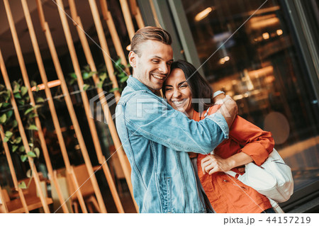Optimistic male hugging smiling lady during conversation Optimistic male hugging smiling lady during conversation 44157219