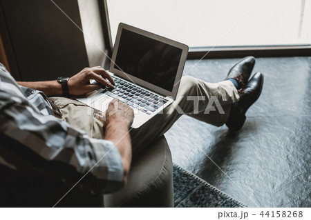 Man is typing on laptop in living room Man is typing on laptop in living room 44158268