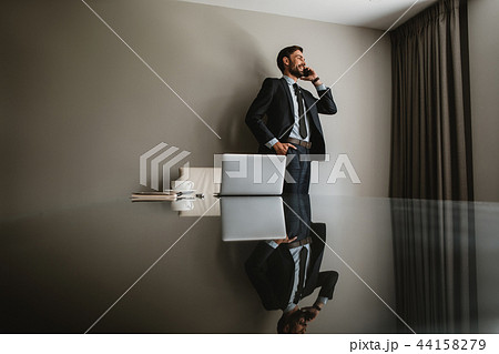 Smiling executive is talking on smartphone in cabinet Smiling executive is talking on smartphone in cabinet 44158279