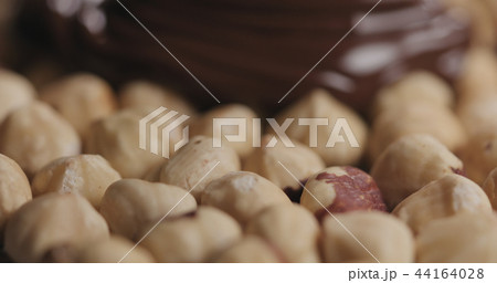 closeup covering roasted hazelnuts with melted dark chocolate 44164028