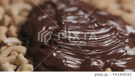 closeup covering roasted cashew with melted dark chocolate 44164032