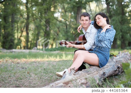 young couple walking in the forest, playing guitar young couple walking in the forest, playing guitar 44165364
