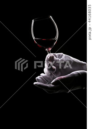 Contours of hands in white gloves hold wine glass 44168035