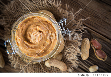 Glass jar with peanut butter on wooden background 44173405