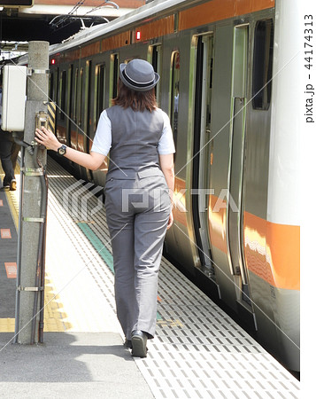 発車ベルスイッチを切ろうと構える女性車掌さんの写真素材