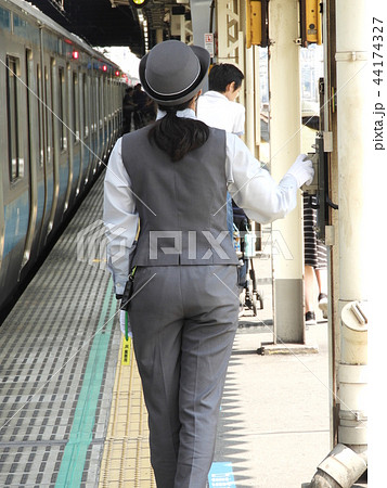 姿勢よく乗降監視している女性車掌さんの写真素材