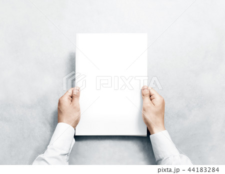 Hand holding white journal with blank cover mockup. 44183284