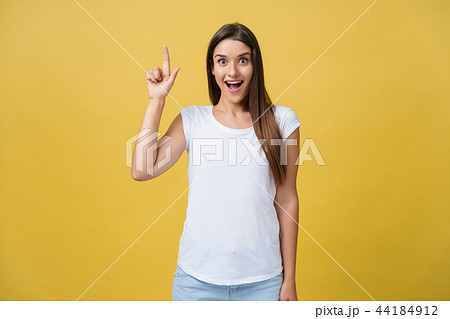 Amaze young woman pointing to one side with her finger while opening her mouth against a yellow Amaze young woman pointing to one side with her finger while opening her mouth against a yellow 44184912