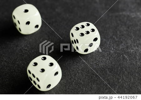 Three fluorescent dice on a dark background. 44192067