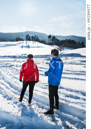 A rear view of senior couple runners standing in winter nature, resting. 44194477