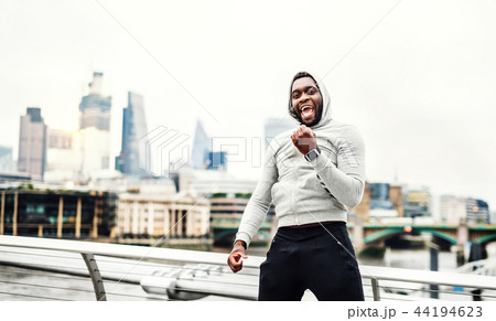 Black man runner with smart watch on the bridge in a city, resting. 44194623