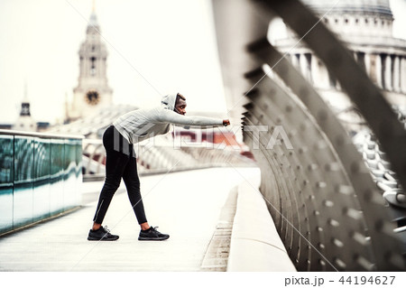 Black man runner on the bridge in a city, stretching. 44194627