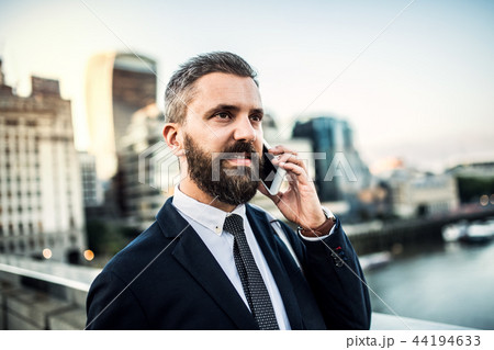 A close-up of hipster businessman with smartphone in the city, making a phone call. 44194633