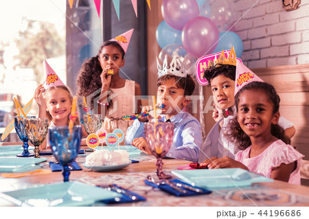 Five cute children sitting at the table and blowing party horns 44196686
