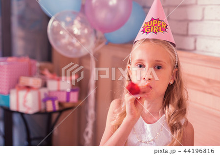 Little girl looking cute while blowing her party horn Little girl looking cute while blowing her party horn 44196816