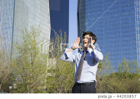 Cheerful young businessman walking in park near office building in the background. Spend time in park with collegue near office. 288 Cheerful young businessman walking in park near office building in the background. Spend time in park with collegue near office. 288 44203857