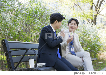 Cheerful young businessman walking in park near office building in the background. Spend time in park with collegue near office. 270 44203997