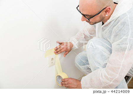Painter sticking the tape near the plug Painter sticking the tape near the plug 44214009