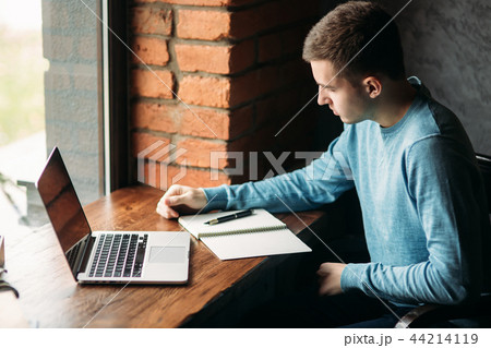 Student working and drinking coffee in a cafe and write down something in the notebook. Prepare for Student working and drinking coffee in a cafe and write down something in the notebook. Prepare for 44214119
