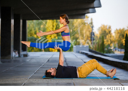 Young man and woman practicing acro yoga on street 44218118