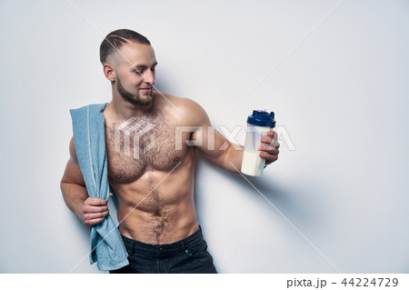 Young muscular man shirtless with towel over shoulders holding rotein drink 44224729