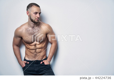 Shirtless muscular man standing by wall contemplating 44224736