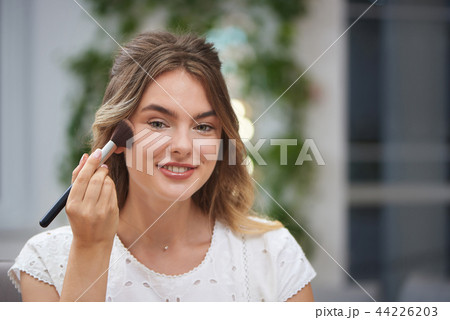 Front view of woman correcting makeup in salon Front view of woman correcting makeup in salon 44226203