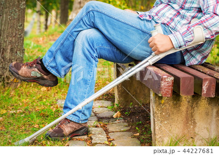 Disabled with crutches in park on bench Disabled with crutches in park on bench 44227681