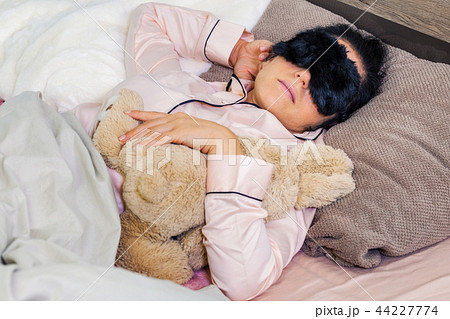 Beautiful woman in sleeping mask and toy bunny in Beautiful woman in sleeping mask and toy bunny in 44227774