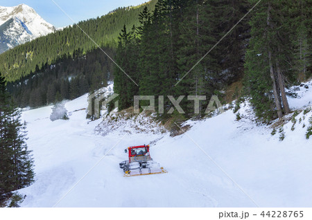 Snow groomer through fir forest and snow Snow groomer through fir forest and snow 44228765