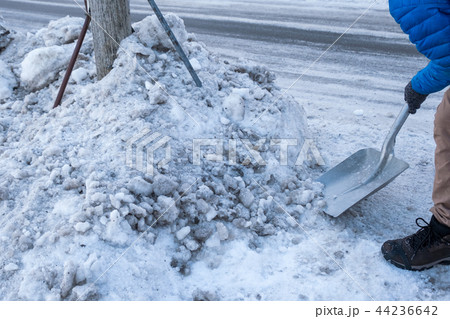 Man clearing snow with shovel on wayside Man clearing snow with shovel on wayside 44236642