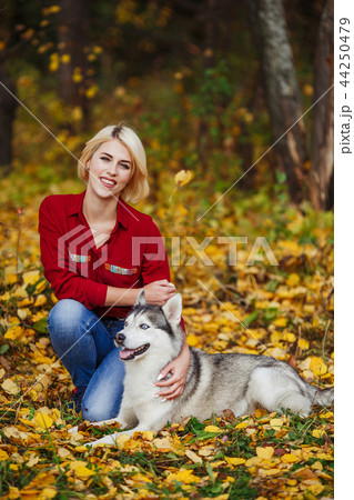 Caucasian girl plays with husky dog in autumn park 44250479