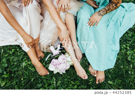 feet of the bride and her bridesmaids on the green grass in summer time 44252385
