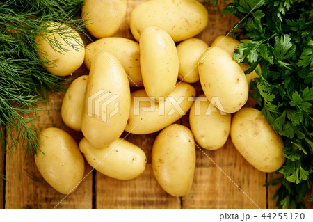 fresh new potatoes and a bunch of dill and parsley on an old wooden table 44255120