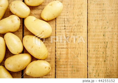 lots of fresh and young potatoes on an old wooden table 44255152