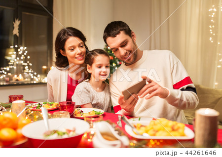 family with smartphone having christmas dinner family with smartphone having christmas dinner 44261646