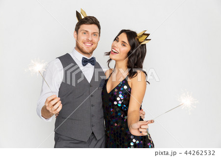 happy couple with crowns and sparklers at party 44262532