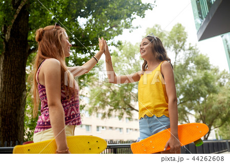 teenage girls with skateboards making high five 44262608