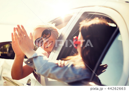 happy teenage girls or women in car at seaside 44262663