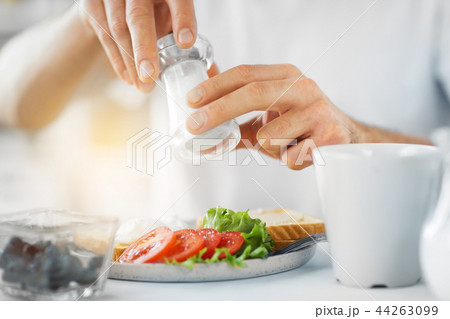 close up of male hands seasoning food by salt mill 44263099
