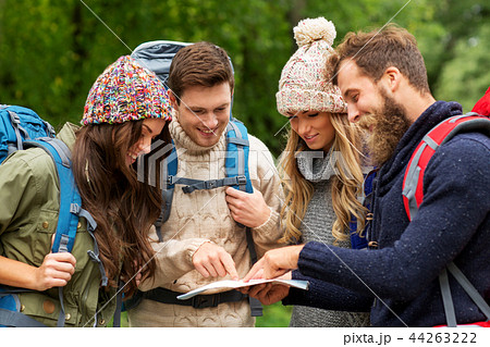 friends or travelers hiking with backpacks and map 44263222