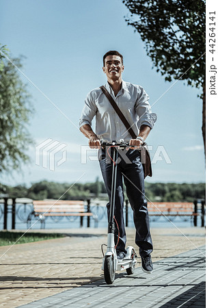 Jolly appealing guy lurching forward on scooter 44264141