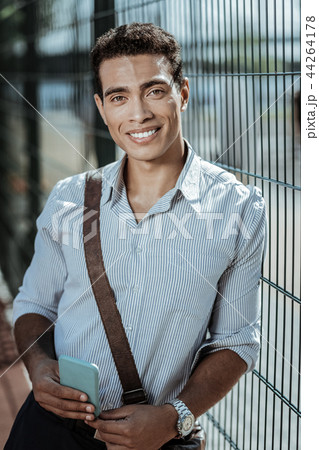 Happy jovial guy awaiting friend near fence 44264178