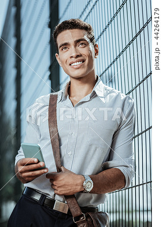 Positive appealing guy getting news on phone Positive appealing guy getting news on phone 44264179