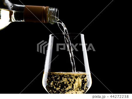 Pouring white wine from bottle to glass on black Pouring white wine from bottle to glass on black 44272238
