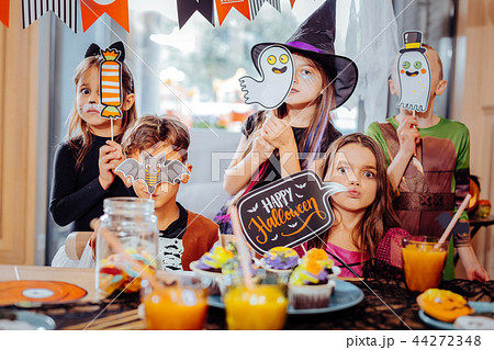 Boys and girls wearing costumes holding pictures and signs devoted to Halloween Boys and girls wearing costumes holding pictures and signs devoted to Halloween 44272348