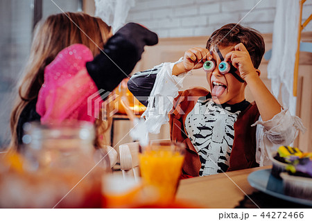 Cute boy putting cookies in the form of eyes to his face celebrating Halloween 44272466